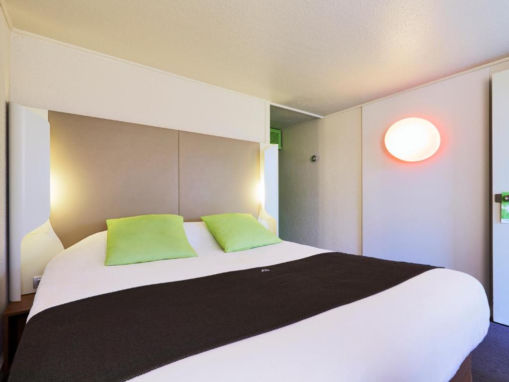 - une chambre avec un grand lit et 2 oreillers verts dans l'établissement Campanile Saint-Etienne Est- Saint-Chamond, à Saint-Chamond