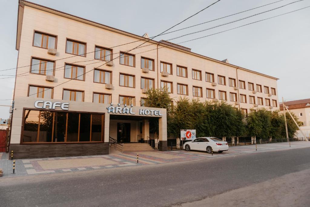 um edifício com um carro estacionado em frente em Aral Hotel em Aralʼsk