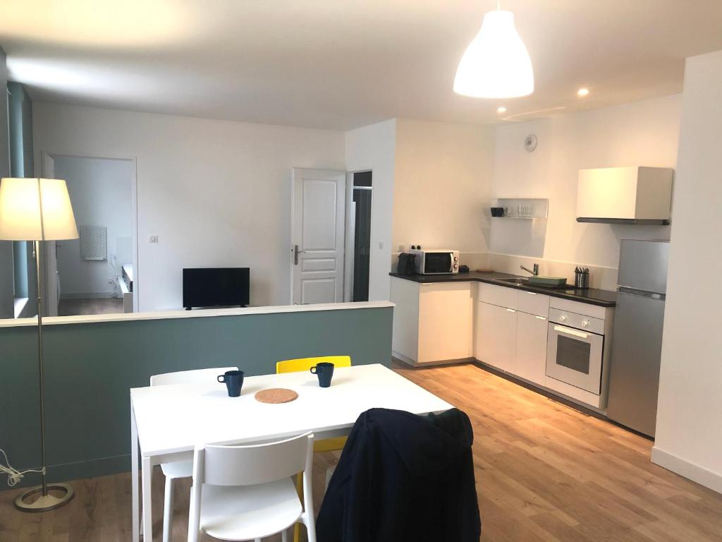 a small kitchen with a white table and chairs at Apprt calme 2 chambres, proche thermes et centre ville, parking gratuit in Lons-le-Saunier