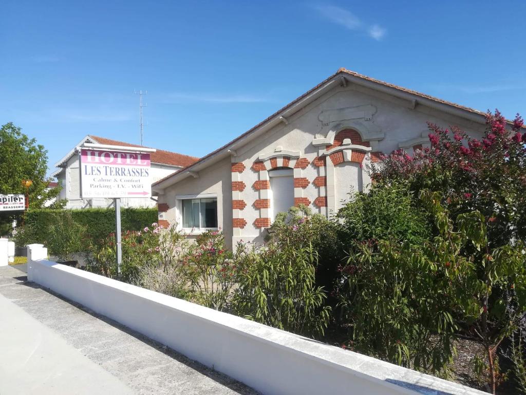 una casa con un cartel delante de ella en Contact HOTEL LES TERRASSES en Le Verdon-sur-Mer