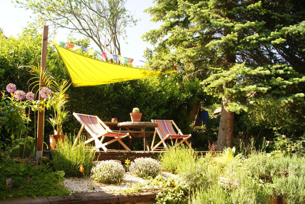 a yellow hammock in a garden with a table and chairs at Gîte du Thalala in Bernardvillé