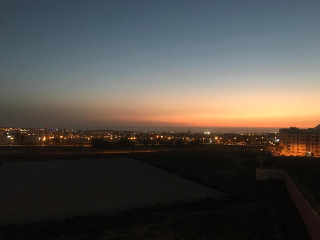 einen Blick auf den Sonnenuntergang über einer Stadt in der Nacht in der Unterkunft Scenic Family Apt overlooking Agadir in Agadir