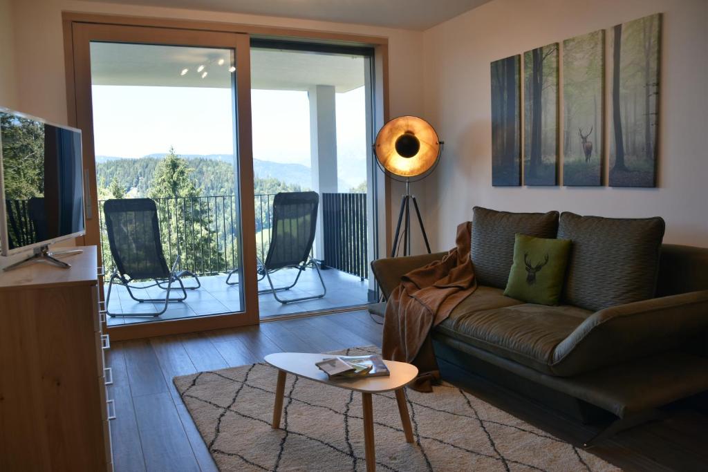 ein Wohnzimmer mit einem braunen Sofa und einem Balkon in der Unterkunft Panoramaresidence Hafling in Avelengo