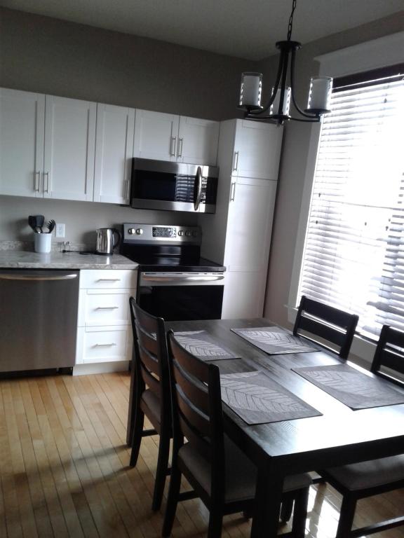 a kitchen with a table and chairs and a kitchen with white cabinets at Executive Suites Bathurst in Bathurst