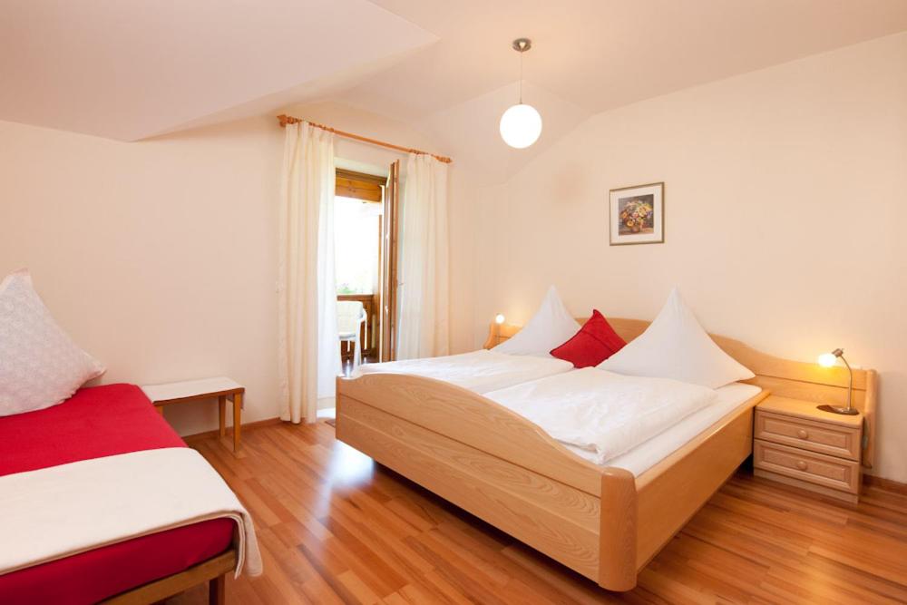 1 dormitorio con 1 cama con sábanas blancas y almohadas rojas en Ferienwohnung Schreiner, en Hohenau