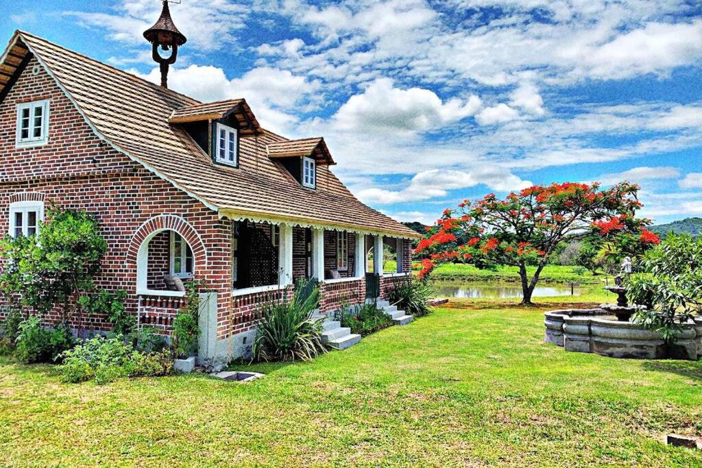 a small brick house with a grass yard at Aconchegante Casa de Hospedagem Enxaimel in Timbó