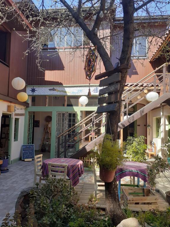 un edificio con mesa, sillas y un árbol en Eco-Hostal Tambo Verde, en Santiago