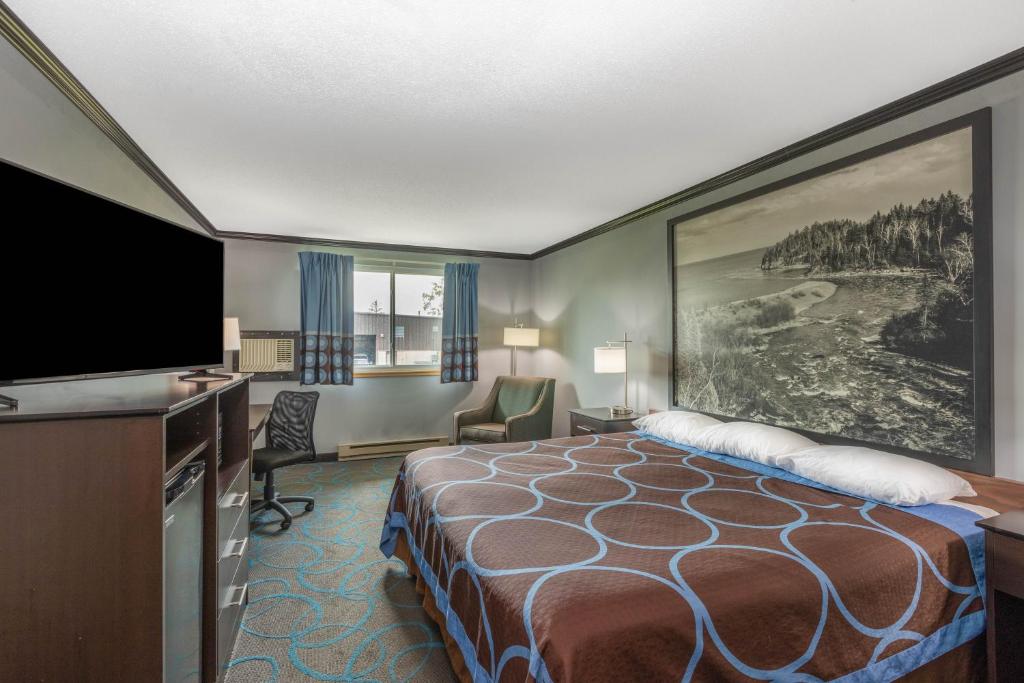 a hotel room with a bed and a flat screen tv at Super 8 by Wyndham Duluth in Duluth