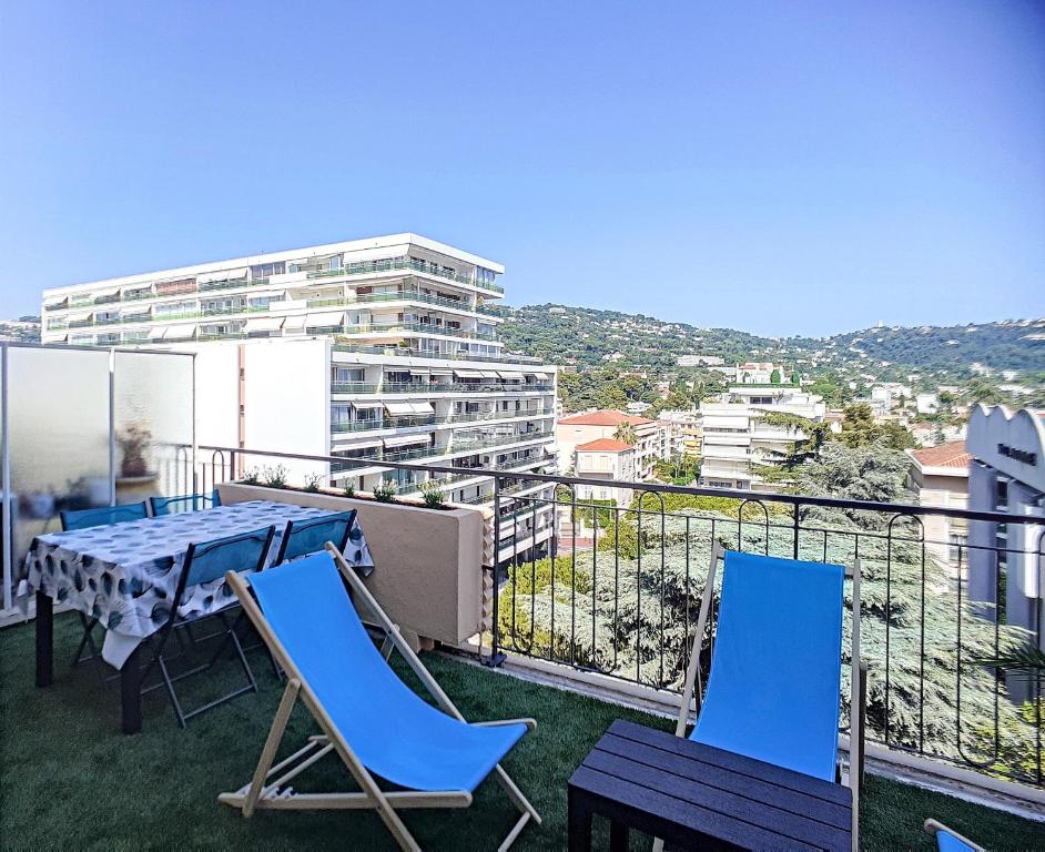 un balcón con sillas azules y una mesa y un edificio en ROOFTOP#PLAGES#APERCU MER#CLIM#Festival en Cannes