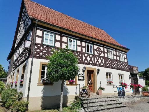 un gran edificio blanco y marrón con un árbol delante en Landgasthof Fischer, en Lichtenfels