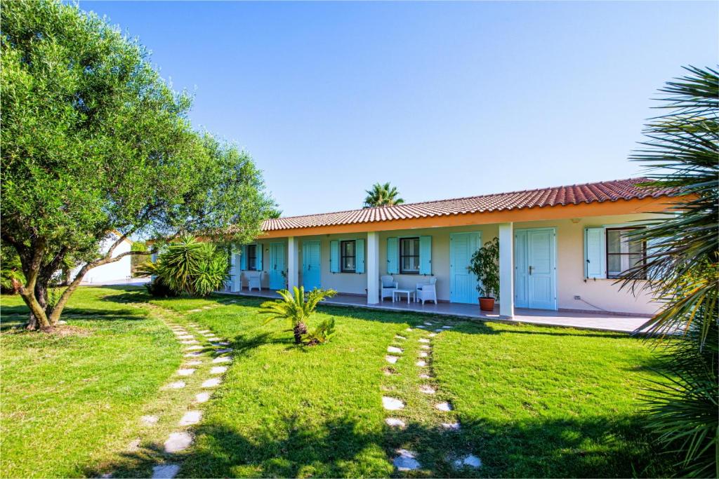 a house with a green lawn and trees in front of it at Agriturismo Is Cortillaris in Càbras