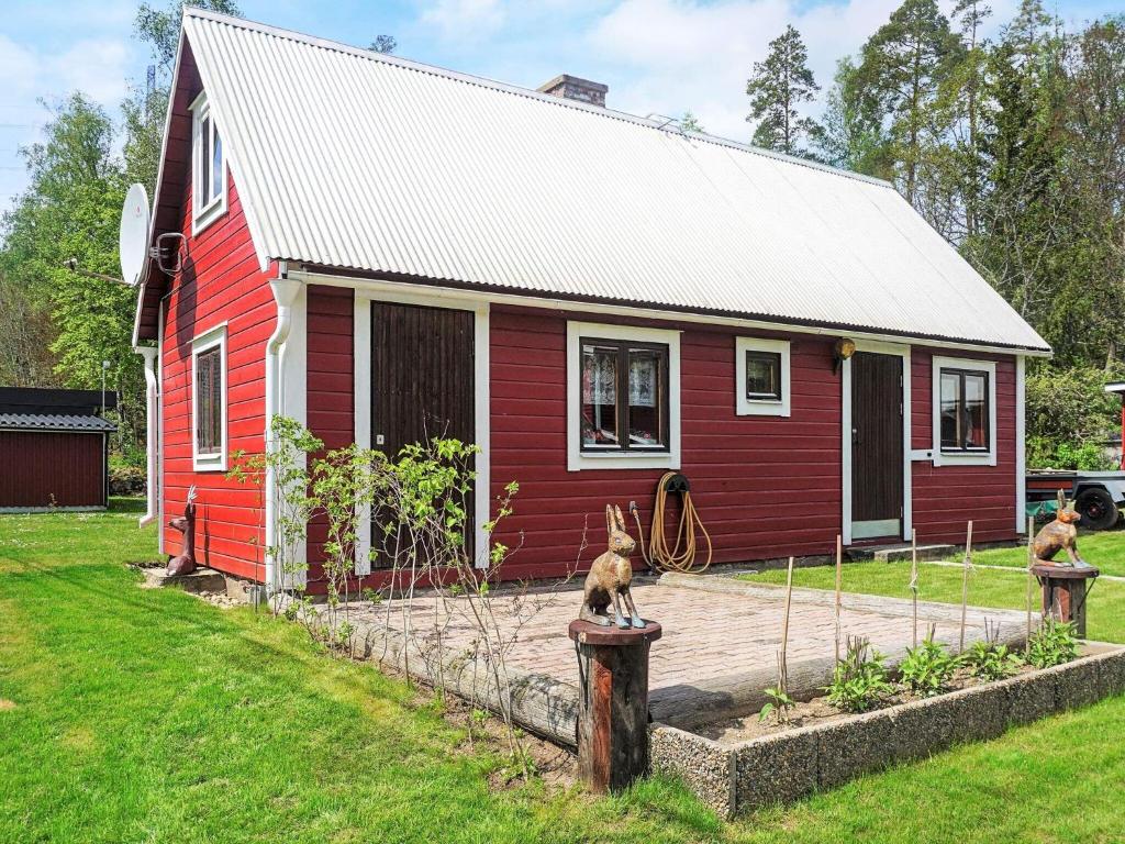 une maison rouge avec deux chiens assis à l'extérieur dans l'établissement Holiday home OLOFSTRÖM II, à Olofström