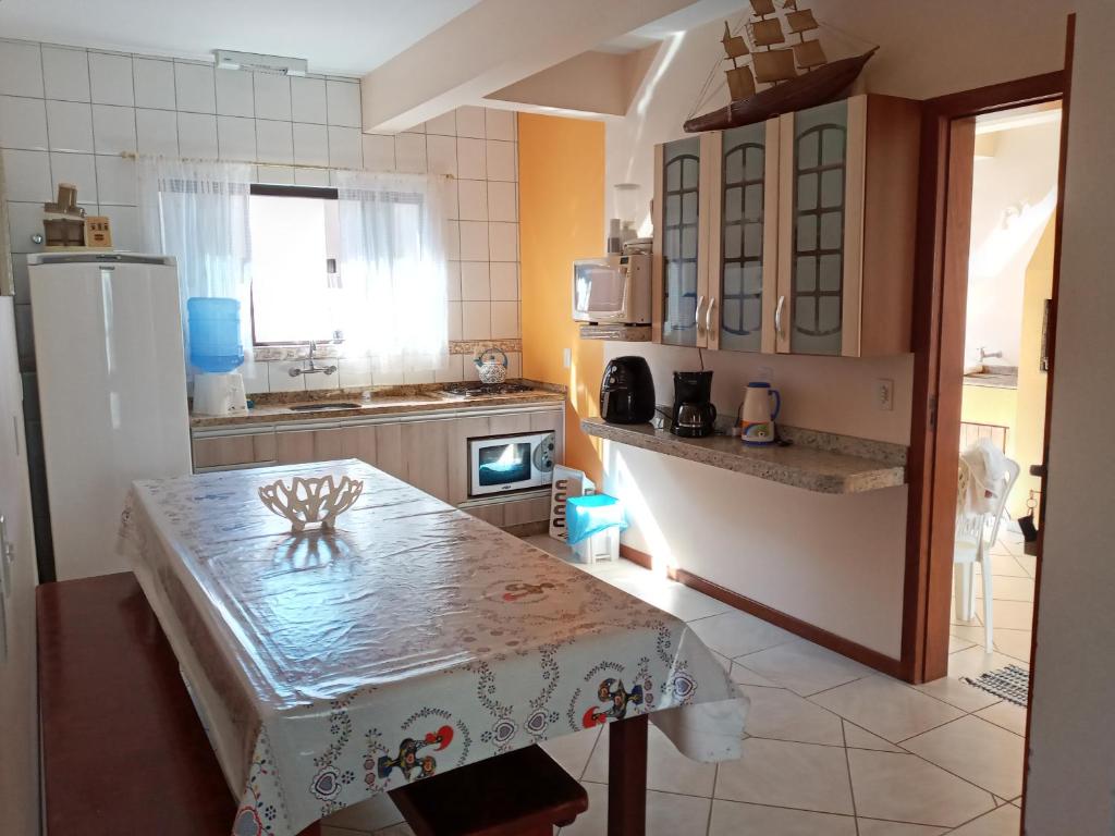una pequeña cocina con mesa y nevera en Casa 3Jotas, en Garopaba