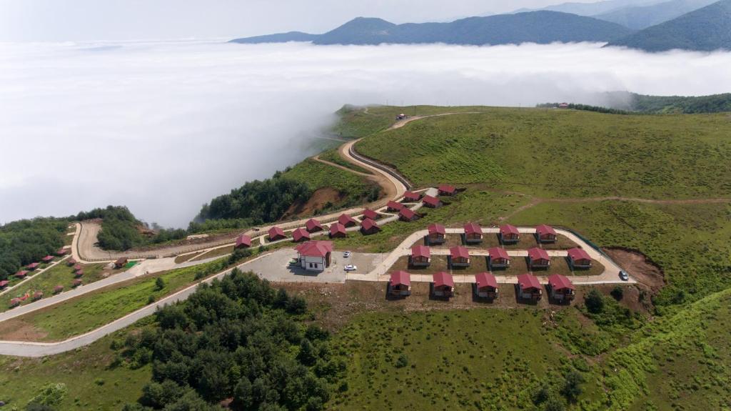 Flora Handüzü Resort Bungalow في ريزي: اطلالة جوية على منزل على تلة في الغيوم