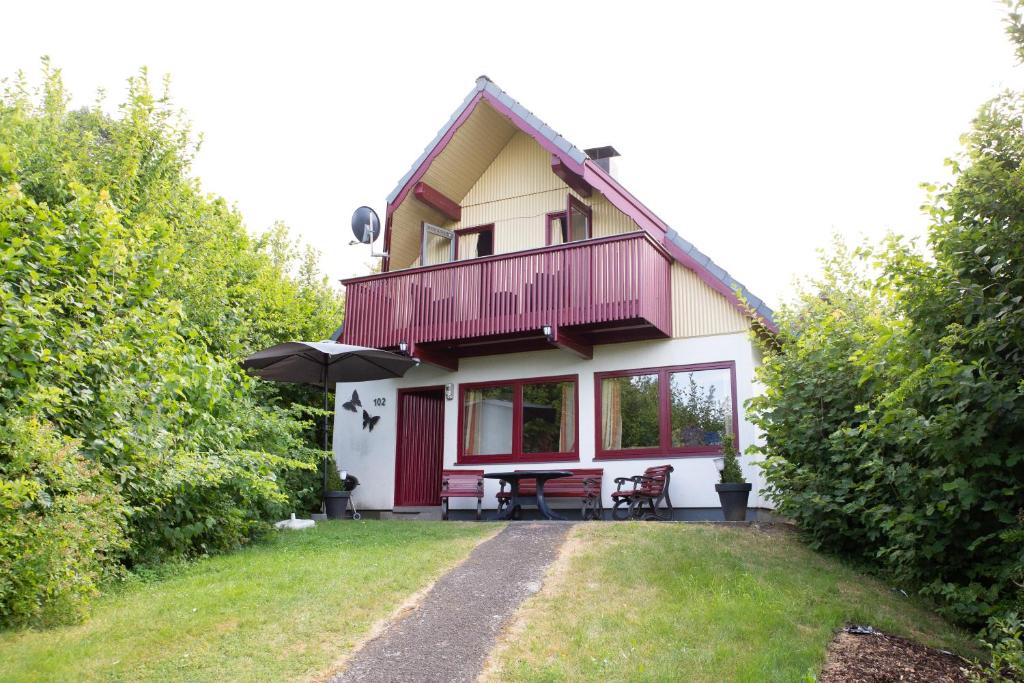 ein Haus mit einem Balkon und einem Tisch mit einem Sonnenschirm in der Unterkunft Ferienhaus am See im Bergland "Schmetterling" in Kirchheim