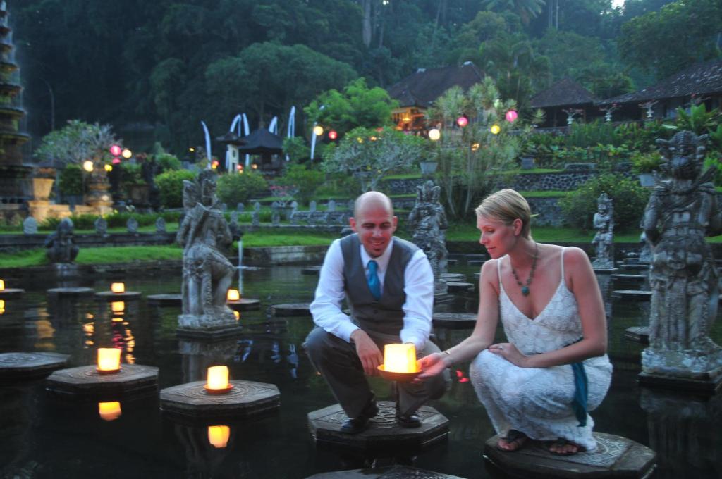 a man and a woman holding candles in a garden at Tirta Ayu Hotel and Restaurant in Tirtagangga