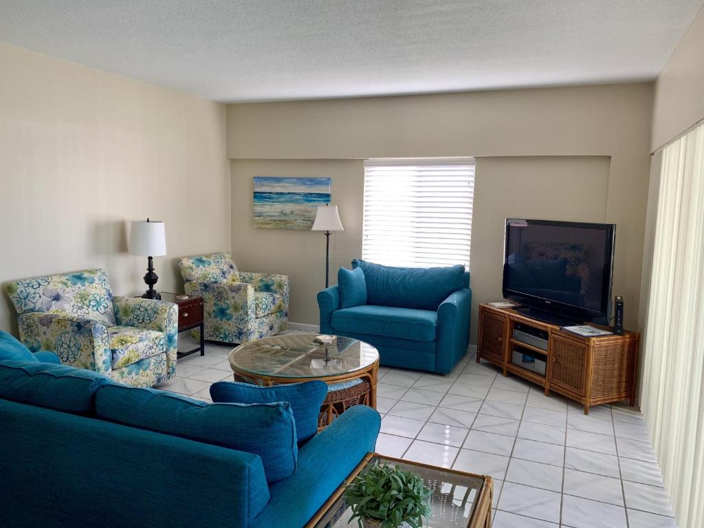 a living room with blue couches and a tv at Island House Beach Resort 12N in Point O'Rocks