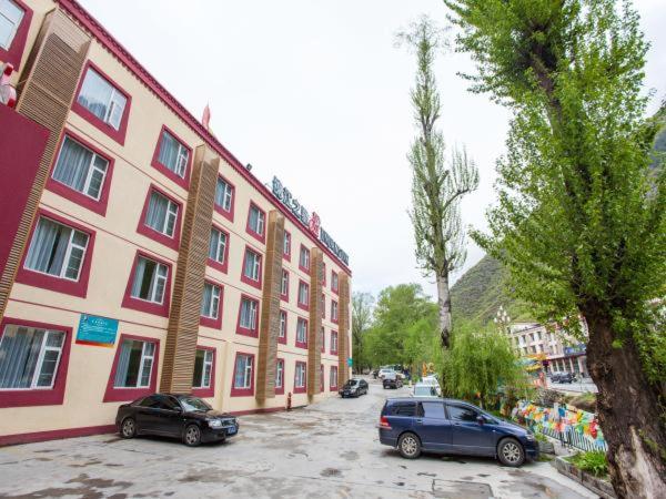 2 voitures garées dans un parking à côté d'un bâtiment dans l'établissement Jinjiang Inn Jiuzhaigou Scenic Resort, à Tazang