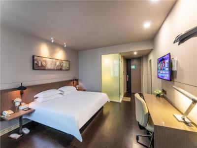 ein Hotelzimmer mit einem Bett, einem Schreibtisch und einem Computer in der Unterkunft JinJiang InnSelect Suzhou Shengze Shunhuxilu Hotel in Suzhou