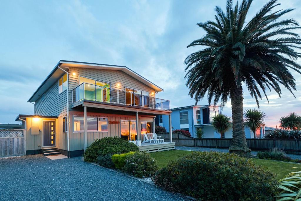 a house with a palm tree in front of it at The Lookout Spacious Stunning Views in Kaikoura