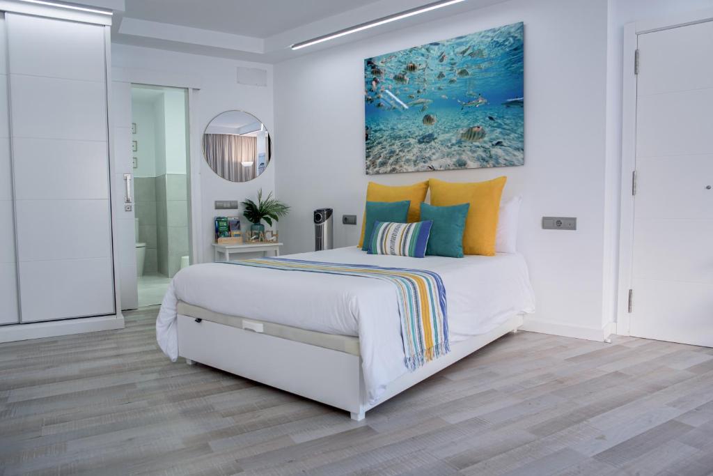 a white bedroom with a large bed with colorful pillows at CANARIAN HOLIDAY HOME - Guest House Gran Canaria in San Bartolomé de Tirajana