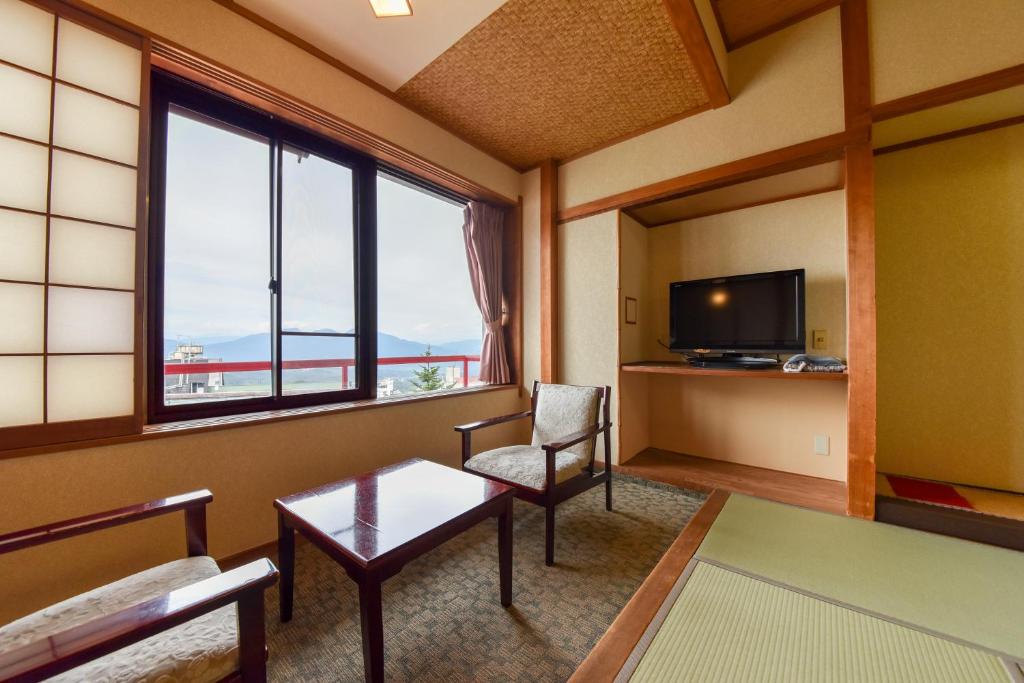 a living room with a couch and a table and a tv at Kokuya in Shibukawa