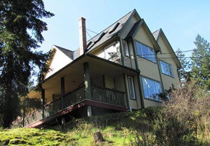 a large house sitting on top of a hill at Wisteria Honeymoon Cottage in Sooke