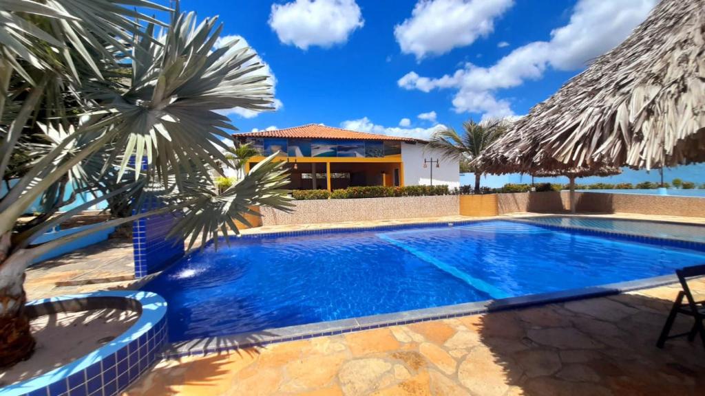 a swimming pool with palm trees in front of a house at Recanto das Arvores in Barreirinhas