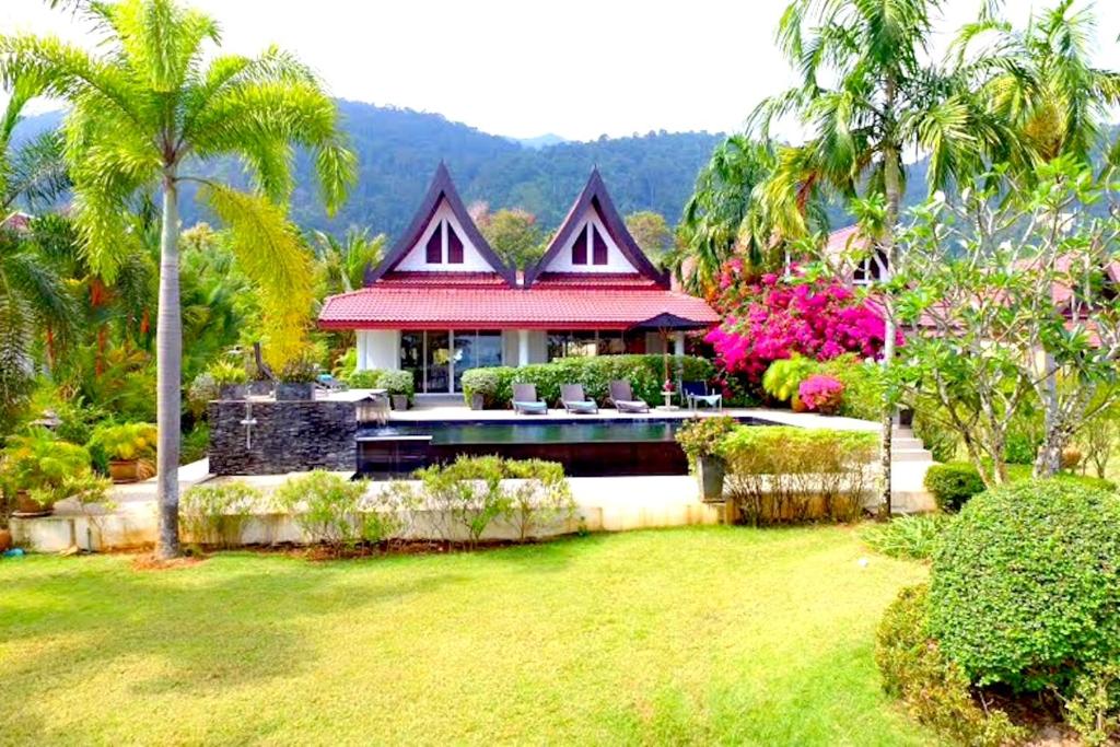 a house with a red roof in a yard at Koh Chang Beach Front 5 Bedroom Villa in Ko Chang