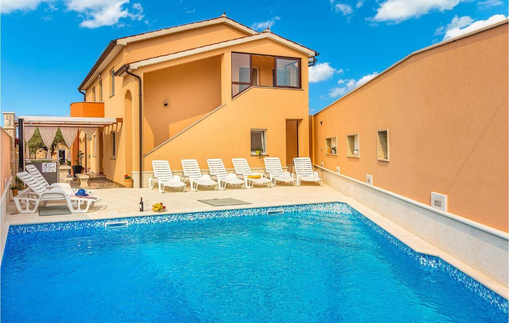 a swimming pool with chairs and a house at Amazing Home In Galizana With Kitchen in Galižana