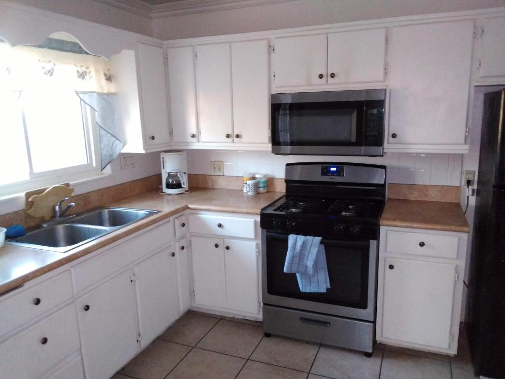a kitchen with white cabinets and a stove and a sink at Home Sweet Home in Colton