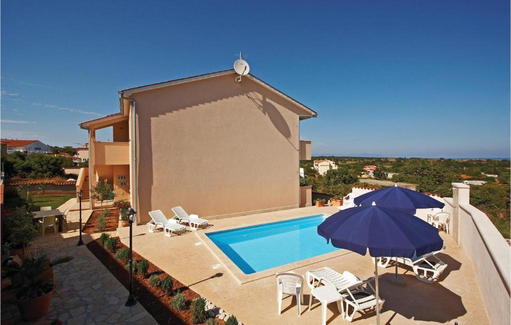 uma piscina com cadeiras e um guarda-sol ao lado de uma casa em 5 Bedroom Stunning Home In Liznjan em Ližnjan