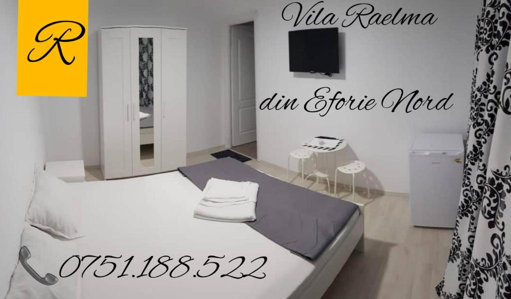 a bedroom with a white bed and a tv at Vila Raelma in Eforie Nord