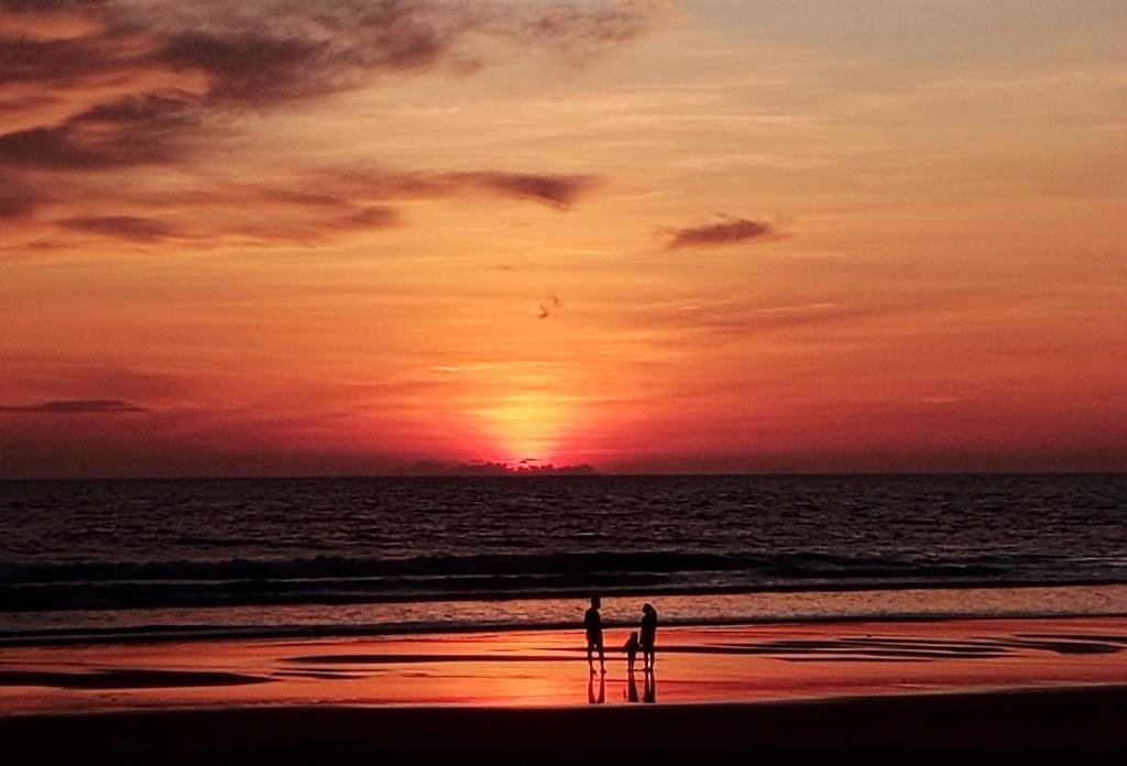 Due persone in piedi sulla spiaggia al tramonto di OmBodhi Retreat a Kumta