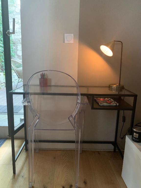 a glass chair sitting next to a desk with a lamp at T2 centre ville avec extérieur in Avignon
