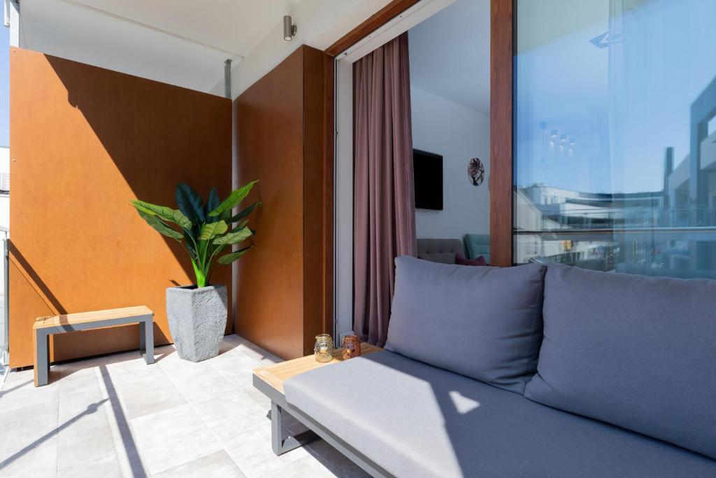 a living room with a couch and a potted plant at Gold Flamingo Apartament by Renters in Międzyzdroje