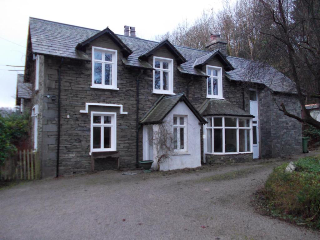 a brick house with white windows and a driveway at Landing Cottage Guest House in Newby Bridge