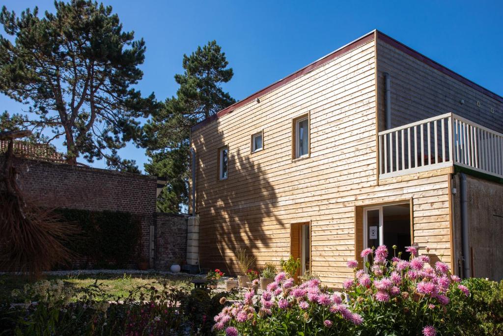 ein Backsteinhaus mit einem Baum und Blumen in der Unterkunft Chambre d'hôtes des pins in Cayeux-sur-Mer