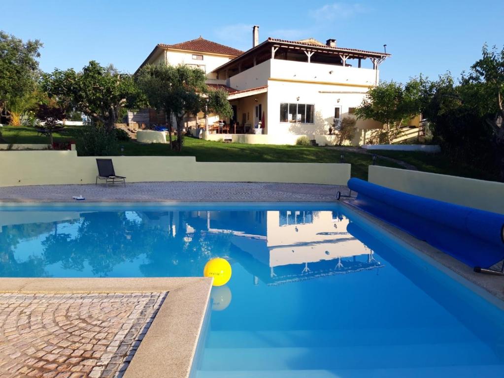 a swimming pool in front of a house at A Casa Amarela in Pinheiro de Coja