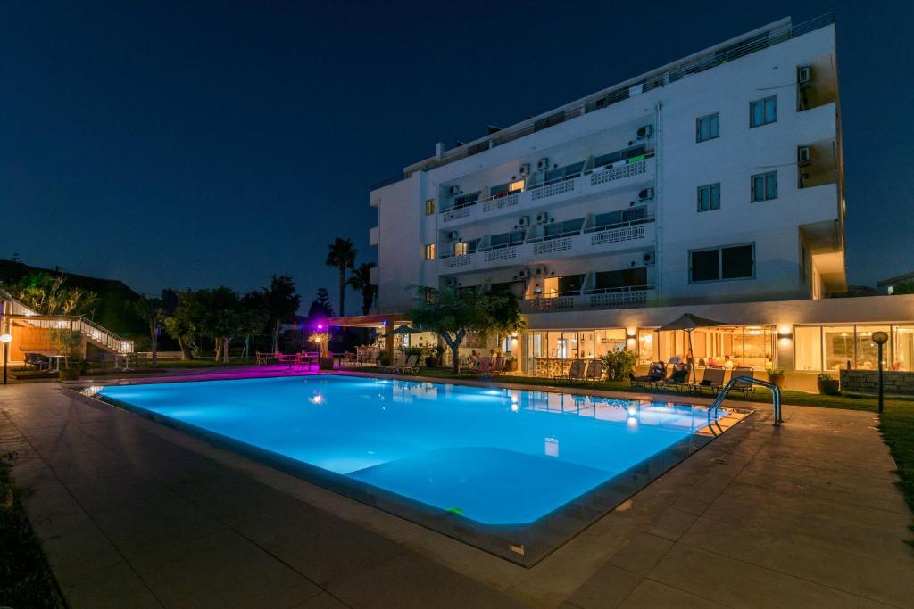 a swimming pool in front of a building at night at Matala Bay Hotel & Apartments in Matala