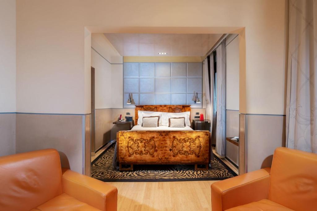 a bedroom with a bed and two orange chairs at Ca' Pisani Hotel in Venice