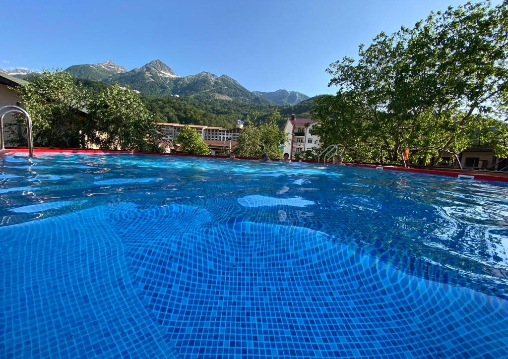 ein großer blauer Pool mit Bergen im Hintergrund in der Unterkunft Juna Aqua Life in Esto-Sadok