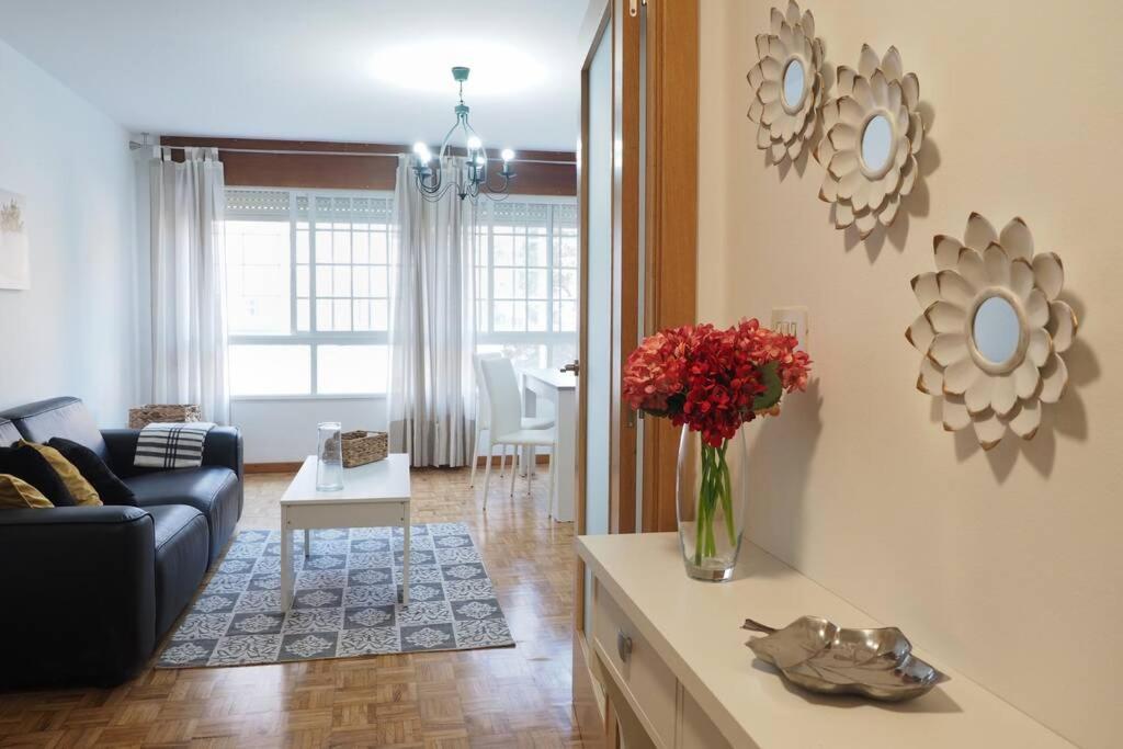 uma sala de estar com um sofá e um vaso de flores em Apartamento El Parque em Padrón