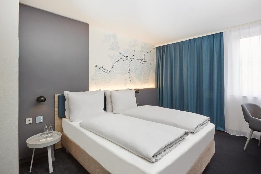 H4 Hotel Leipzig في لايبزيغ: غرفة نوم بسرير ابيض وستارة زرقاء