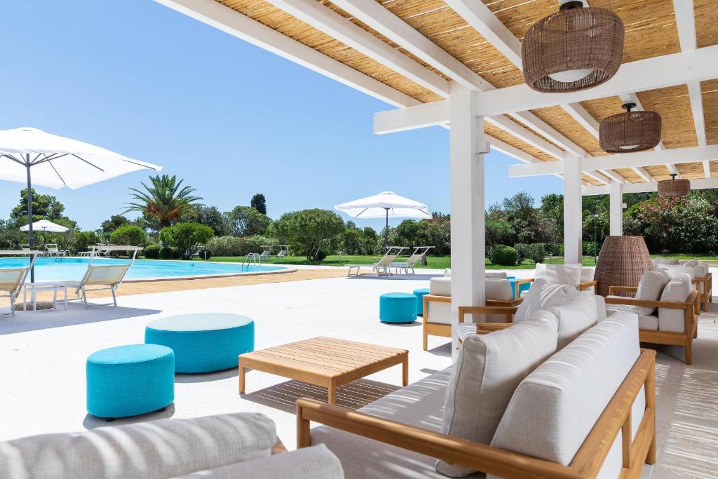 a patio with couches and tables and a pool at Is Molas Resort in Pula