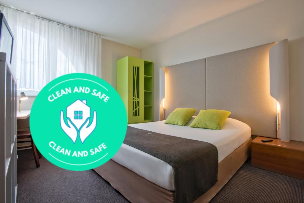 a hotel room with a bed with a green logo at Campanile Łódź in Łódź