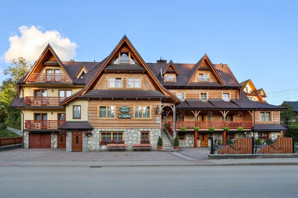 une grande maison en bois avec un toit en gambrel dans l'établissement Galicówka Pokoje Gościnne, à Małe Ciche