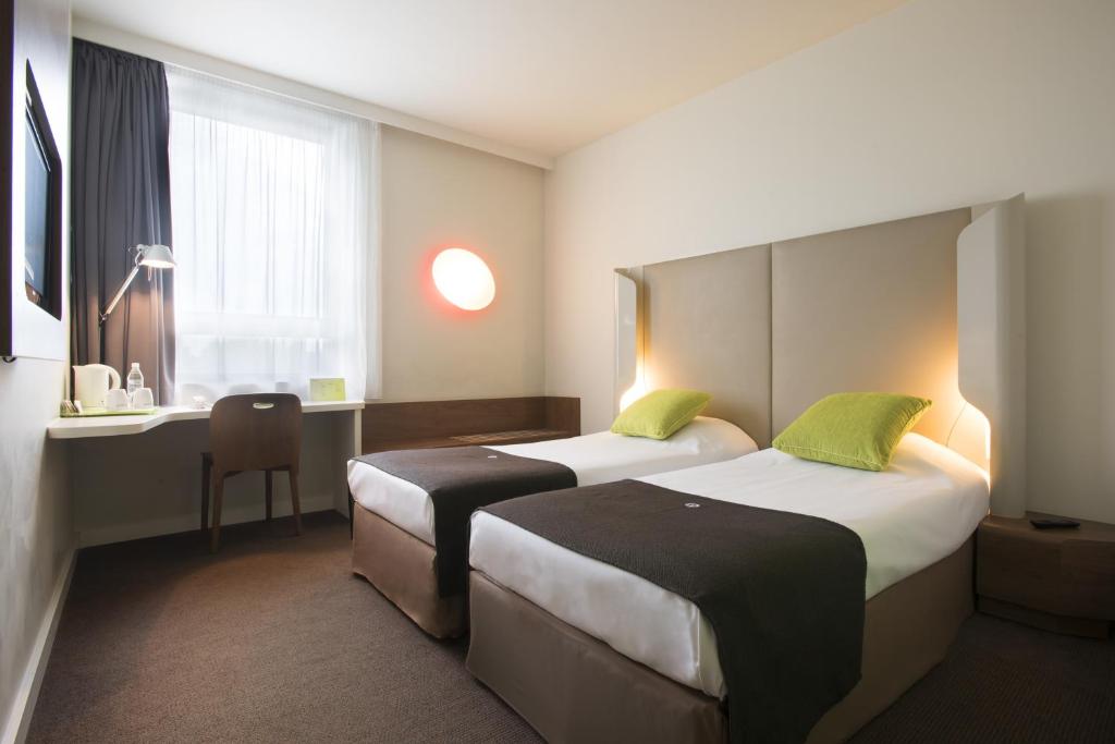 a hotel room with two beds and a desk at Campanile Wroclaw Centrum in Wrocław