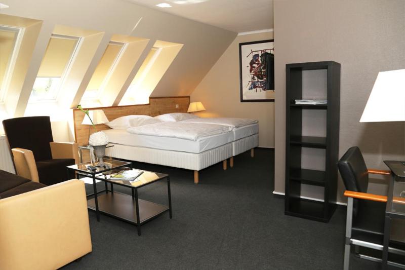 a bedroom with a bed and a living room at Hotel Altstadt-Passage in Wittingen