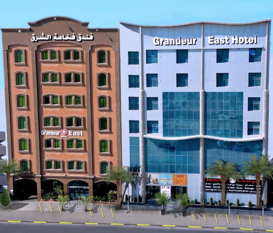 a hotel and a building with palm trees in front of it at Grandeur East in Al Khobar